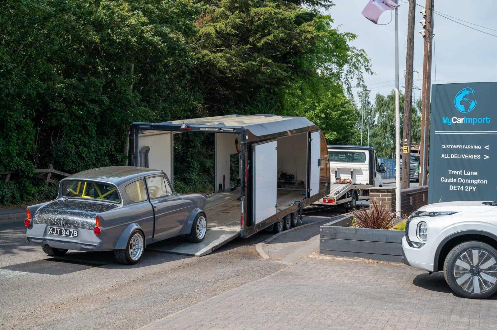 A grey Ford Anglia being unloaded from the back of our enclosed transporter