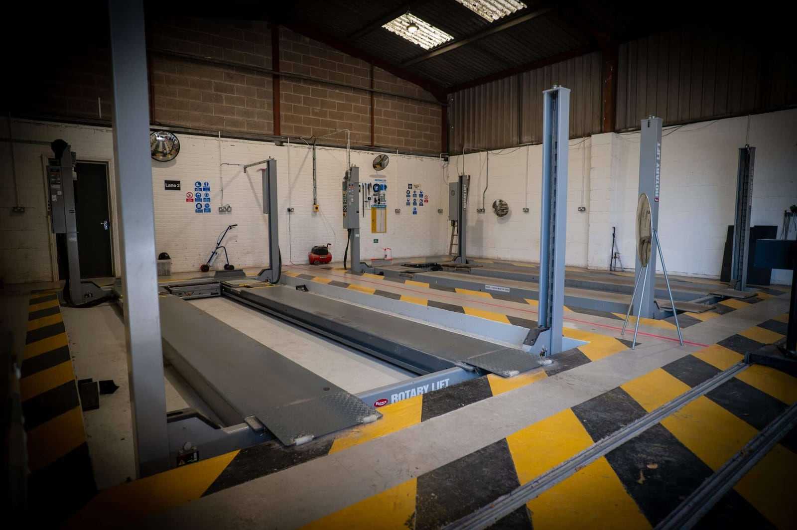 An empty four-post lift in the inspection lane inside our workshop