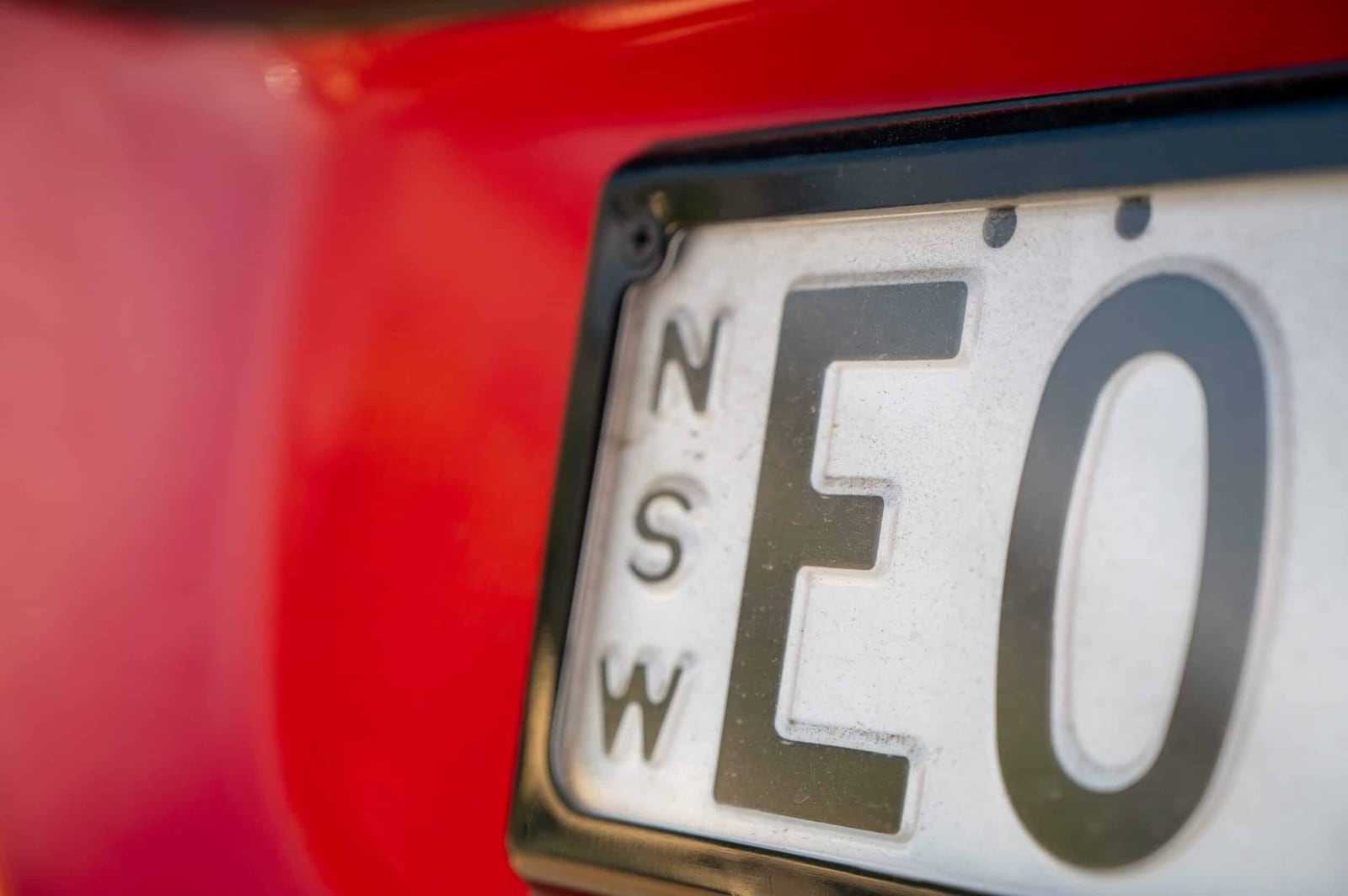 Close-up of a New South Wales number plate on a red car in our yard